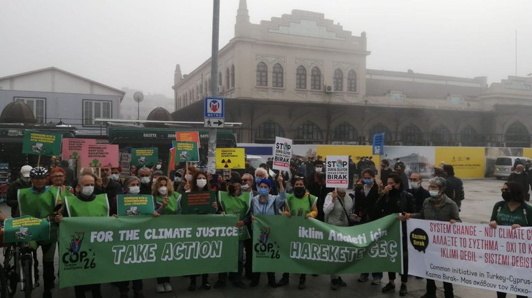 Een groep mensen protesteert voor klimaatoplossingen in Turkije. Het is mistig. In de achtergrond zie je een gebouw.
