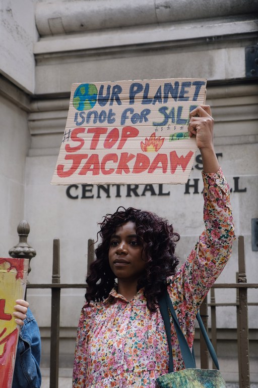 Demonstrant houdt protestbord boven haar hoofd met daarop Our planet is not for sale