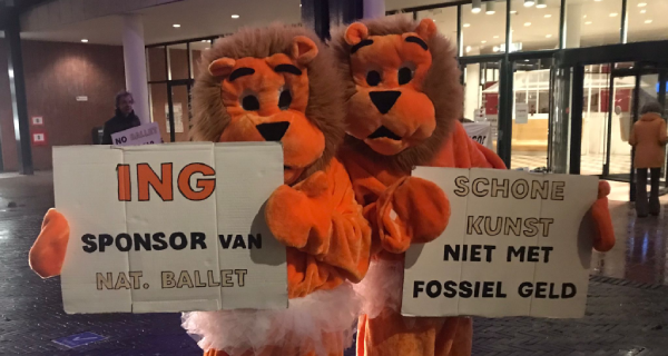 2 mensen in oranje leeuwenpakken voor de stopera in Amsterdam. Ze houden protestborden vast. 2 mensen in oranje leeuwenpakken voor de stopera in Amsterdam. Ze houden protestborden vast.
