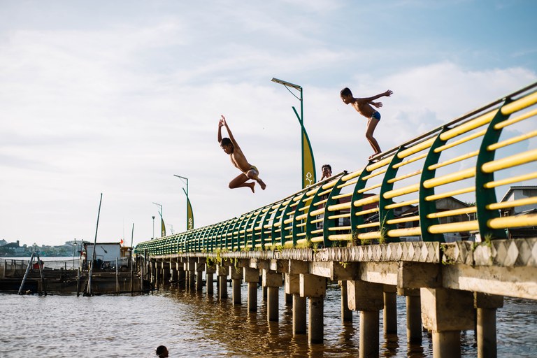 Beeld: Reza Fahlepi. Kinderen springen van de pier.