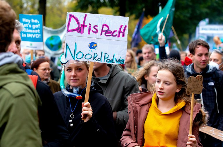 Een activist draagt een protestbordje met daarop de tekst: Dat is pech, noordpool weg. Ze draagt een snorkel en een duikbril. Fotograaf: Bart Hoogveld.