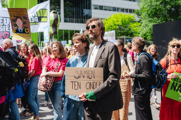 Man houdt protestbord vast 'samen ten onder' op de Zuidas Amsterdam