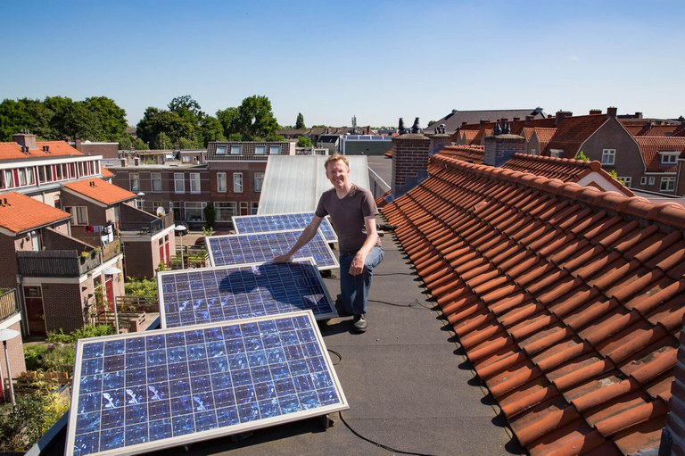 Man bij zonnepanelen op zijn dak