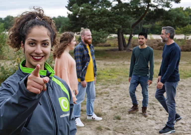 De duurzame oplossingen van Milieudefensie.jpeg Foto van een groep jonge mensen. Op de voorgrond een lachende vrouw met een Milieudefensie-jasje aan. Ze wijst naar jou.